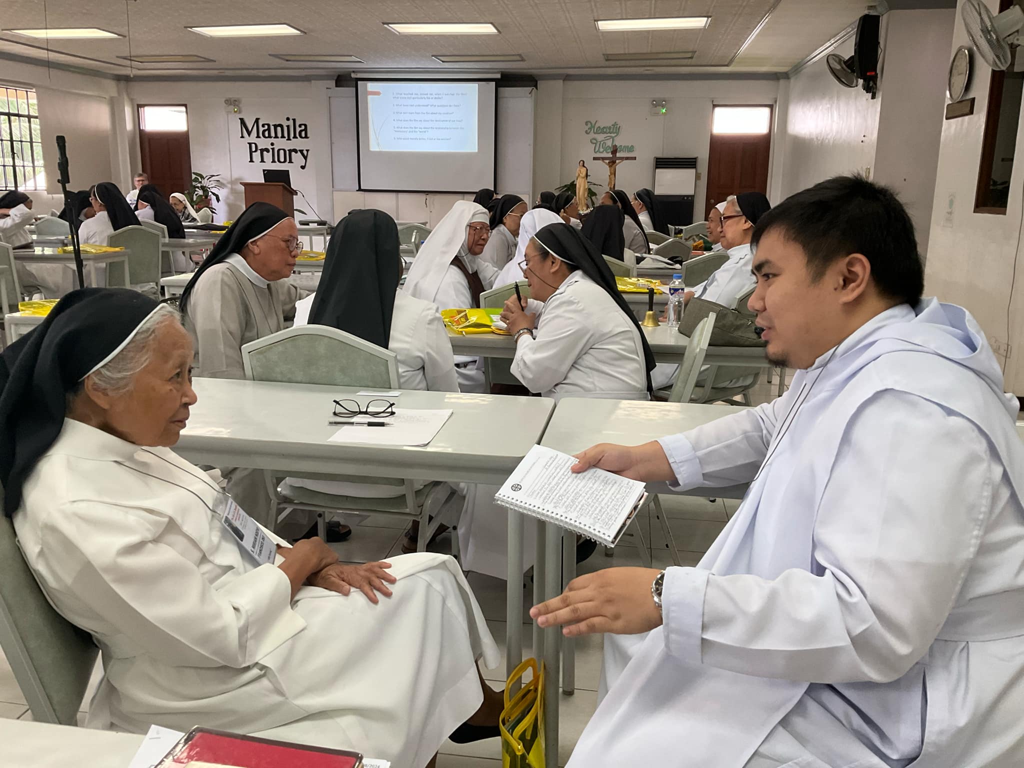 A moment of shared wisdom:. Dom Angelico, OSB engages in thoughtful exchange during the Monastic Course session.